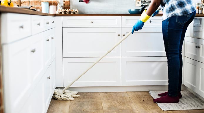 A person is cleaning the floor in a kitchen.